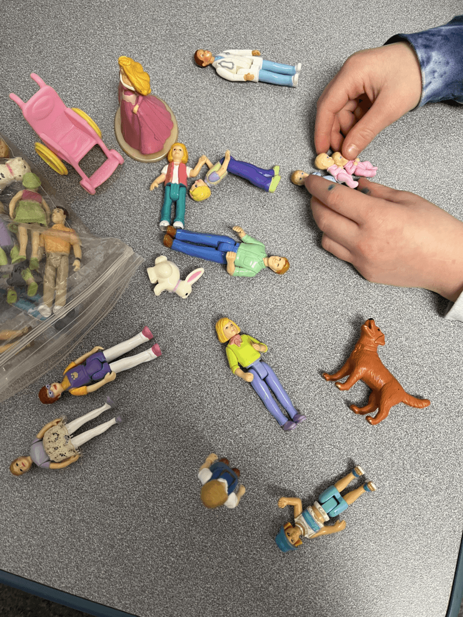 Hands using pretend-play figures during speech therapy
